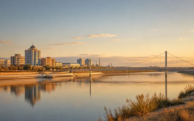 Conceptual Atyrau riverfront at golden hour with the Zhayyk River, a pedestrian bridge, and a low western Kazakhstan skyline