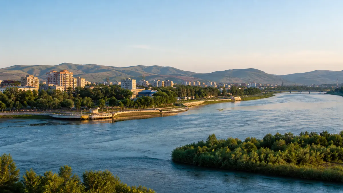 Conceptual contemporary Oskemen riverfront where broad blue water, a green embankment and low Altai foothills frame the city