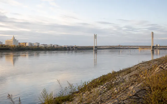Conceptual early-morning Semey riverfront with the Irtysh, a cable-supported bridge and a restrained city skyline