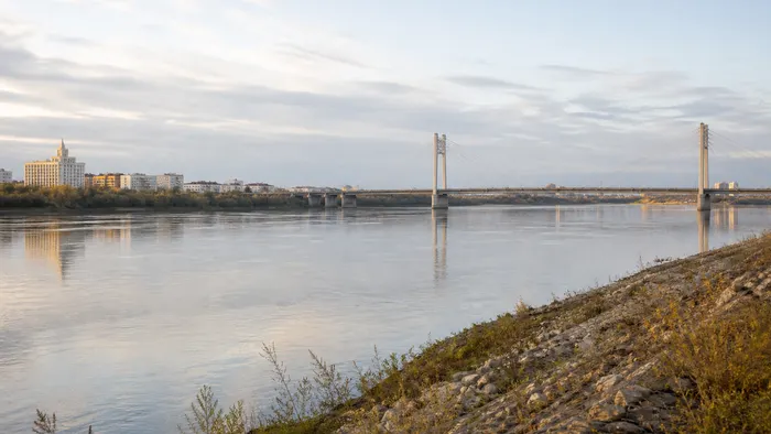 Conceptual early-morning Semey riverfront with the Irtysh, a cable-supported bridge and a restrained city skyline