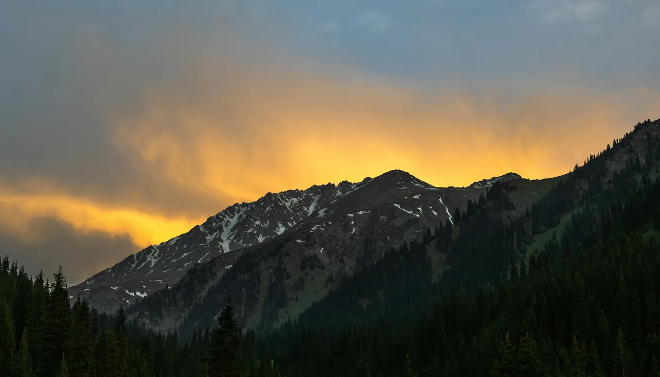 Dark tree-covered mountain ridges beneath a golden evening sky