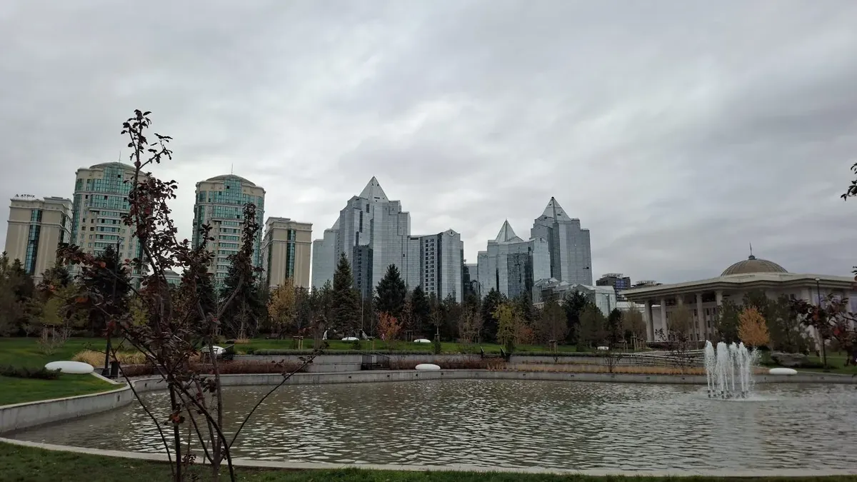 Solo female traveler walking through Almaty's Panfilov Park with mountains in background
