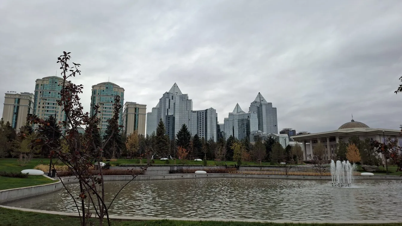Woman travelling independently in Kazakhstan with a city and mountain landscape behind her