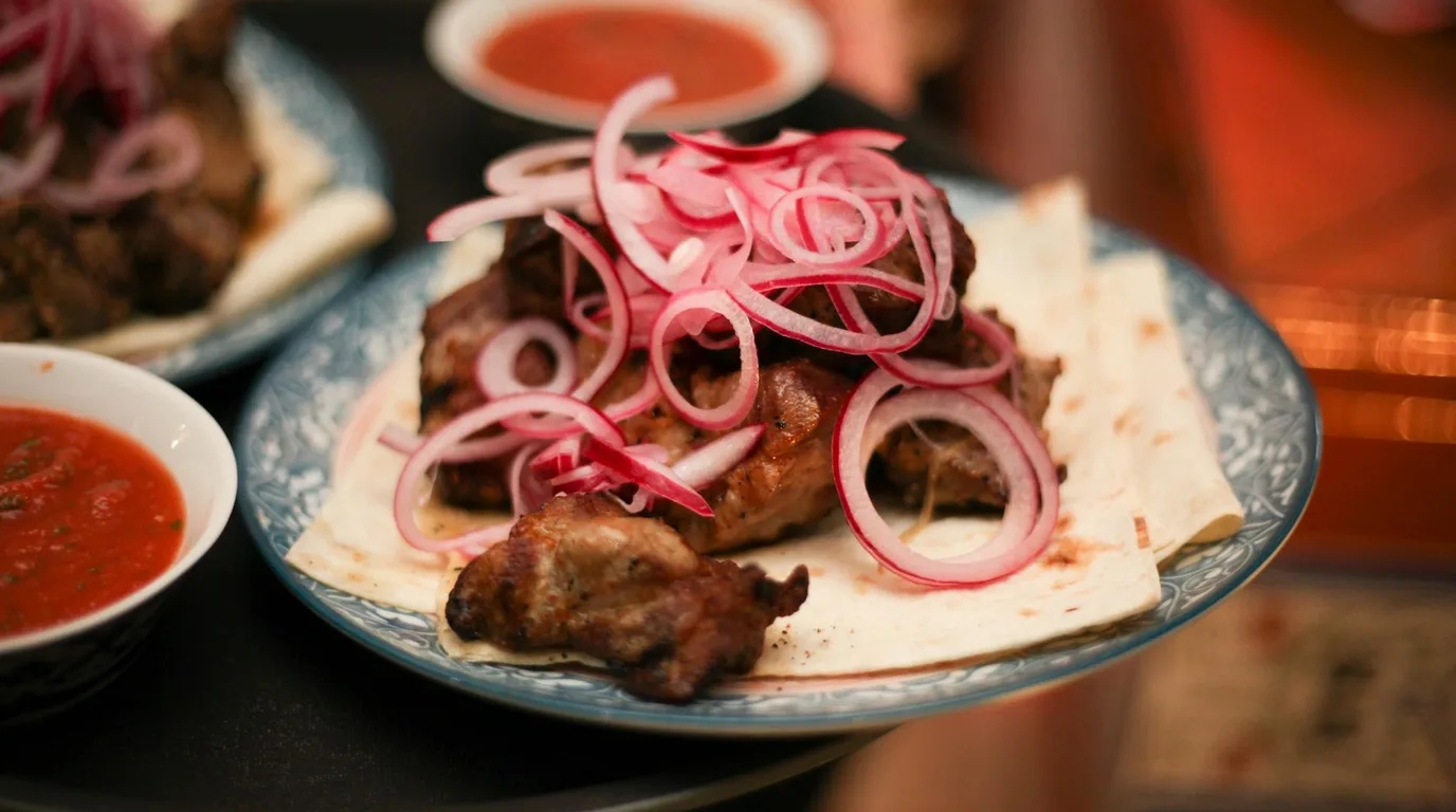 Traditional Kazakh beshbarmak dish with boiled meat and flat noodles on a large communal plate